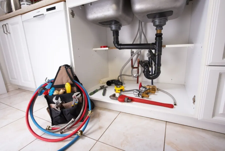 Under-sink plumbing with tools and supply lines